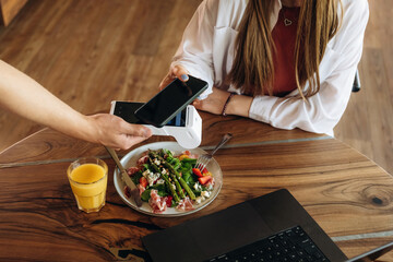Wireless payment by using smartphone. Woman n the cafe restaurant