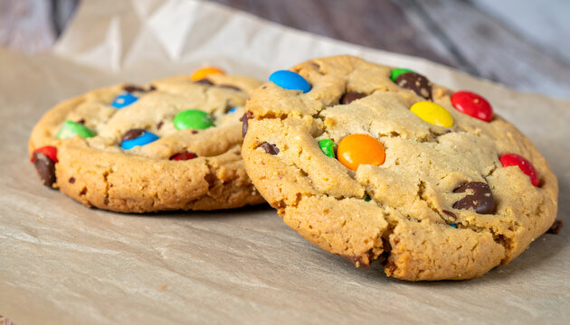 Two Homemade Chocolate Chip Cookies with M&Ms on Parchment Paper