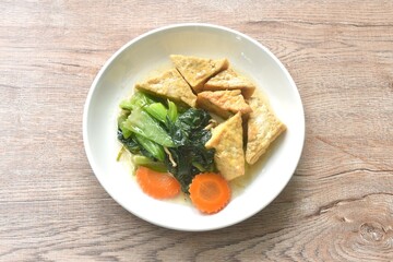stir fried Chinese cabbage with needles mushroom and carrot topping tofu in soy sauce on plate