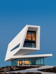 Modern cantilevered building with glass windows on rocky terrain under a blue sky