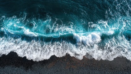 Aerial view of foamy waves crashing on a dark volcanic beach