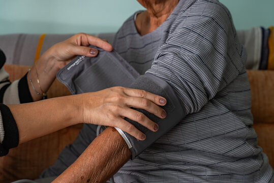 Candid Moment of Latina Woman Checking Blood Pressure of Afro Grandmother at Home