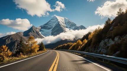 Highway Through Mountain Valley with Snow-Capped Peaks and Autumn Trees