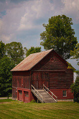 Obraz premium Peacham Historic District, first settled in 1776, in Caledonia County, Vermont, captures a tranquil summer New England landscape over a rustic barn as stormy clouds roll in.