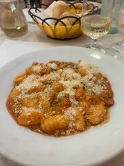 A plate of gnocchi with a Bolognese sauce topped with freshly grated Parmesan cheese