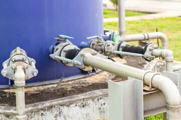 Industrial plumbing system featuring a blue tank with interconnected metal pipes and valves provides a detailed view of the technical infrastructure showcasing utility and engineering expertise