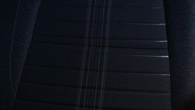 Detailed view of a dark textile surface with parallel stitching and subtle sheen, car seat fabric.
