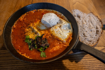 Shakshuka, adapted with Georgian matsoni yogurt. Represents cross-cultural fusion within Georgia's modern food. Eggs poached in spiced tomato sauce and served in a cast iron skillet.