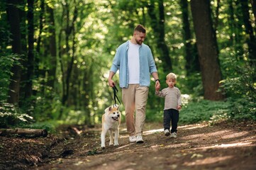 Fototapeta premium Free time, having a walk, wellness. Father with son and dog are in the forest