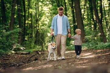 Exploration conception, walking together. Father with son and dog are in the forest