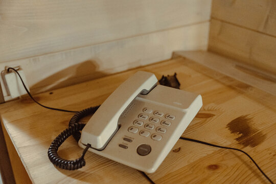 White corded telephone resting on wooden desk in room
