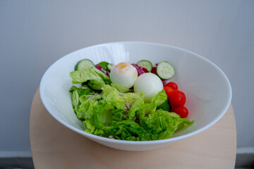Healthy food, a bowl of salad, consist of eggs, lettuce, cherry tomatoes, cucumber, sunflower seeds, and red romaine lettuce