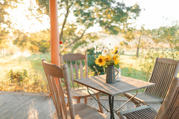 Obraz premium Blue jug filled with yellow sunflowers and white cosmos on rustic outdoor setting at country home