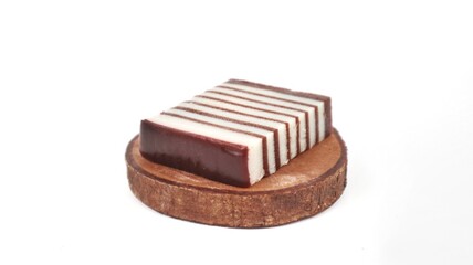 Elegant layered dessert kue lapis traditional, beautifully presented on a small wooden stand against a clean white background.