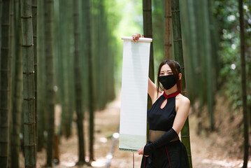 竹林で白紙の巻物を広げる女忍者