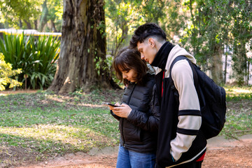 Fototapeta premium Students using smartphone in park, exploring nature and technology