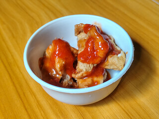 Pentol tofu served in a white bowl, pieces of tofu and meatballs covered in thick red chili sauce. Looks very delicious and delicious.