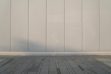 A fragment of a street city metal wall of a building and an paving stones. Building's facade with shadows. © Sopear