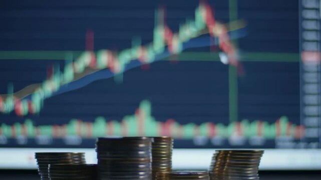 Stacks of coins in front of a stock market graph