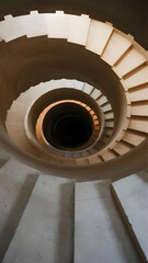 Obraz premium A never-ending spiral staircase made of pale concrete, dim warm lights casting distorted shadows, vanishing into darkness, eerie silence, surreal liminal space