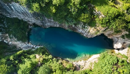 top view of natural rocky pit with deep water surrounded by lush green vegetation