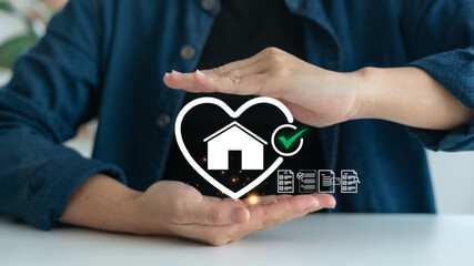 Close-up of hands protecting house icon in heart shape with check mark and document symbols, representing real estate insurance, home safety, property protection, and legal document approval process.