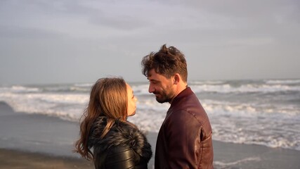 Romantic couple kissing on the beach at sunset in slow motion. Tender moment of love and connection with sea waves in the background. Concept of intimacy, passion and relationship goals.