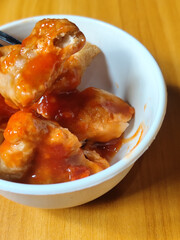 Pentol tofu served in a white bowl, pieces of tofu and meatballs covered in thick red chili sauce. Looks very delicious and delicious.