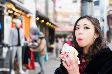 冬の街中で肉まんを頬張る女性