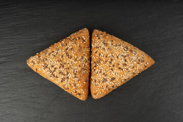 Triangular bun closeup. Wheat bread with sesame and flax seeds, healthy whole grain bakery