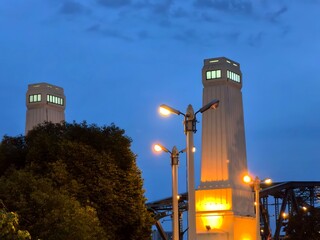 Street lights illuminating a bridge with towers against a twilight sky.