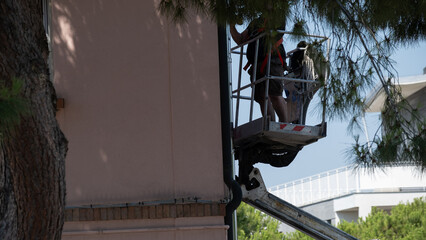 Workers on aerial lift performing maintenance near building facade