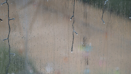 Raindrops on window glass with blurred lights and hanging cords
