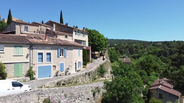 Aerial drone view approaching a hillside village with traditional stone houses and swallows flying nearby. Mediterranean countryside idea. South France travel and landscape concept.