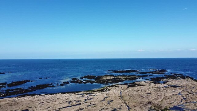 Rocky shoreline and deep blue ocean under a clear sky. Sea and coastline idea. Nature and landscape concept.