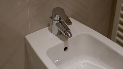 Clean white bidet with chrome faucet in modern hotel bathroom