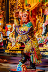 Naklejka premium Inside Bangka Qingshan Temple in Taipei, Taiwan, the main altar also features a statue of Nantian Dashengye, a revered deity known for his power and protection. The statue is dressed in a vibrant robe