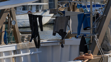 Drying wetsuits and gear on fishing boat in harbor