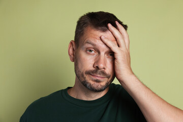 Man suffering from hangover on olive background
