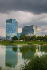 Fototapeta premium Kuchajda lake in Bratislava, nature in town, with vegetation and modern buildings reflecting the light