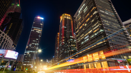 Night view of modern city with illuminated skyscrapers and light trails