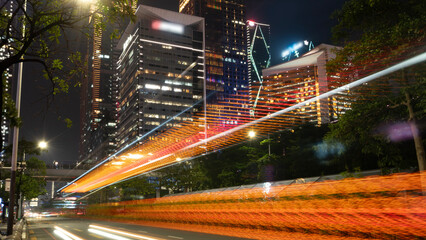 Night city traffic light trails with modern skyscrapers in background