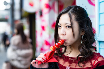 都会の路地でいちご飴を食べる日本人女性のポートレート