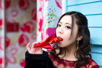 都会の路地でいちご飴を食べる日本人女性のポートレート
