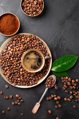 Coffee background - cup of black coffee, coffee beans and ground coffee on a black background top view vertical photo, copy space for text