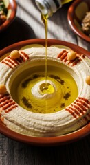 POV shot of traditional Middle Eastern hummus being drizzled with olive oil