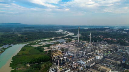 Aerial drone view of a large industrial factory complex with warehouses, chimneys, and storage tanks in Asia