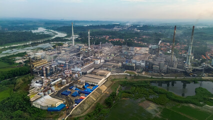Aerial drone view of a large industrial factory complex with warehouses, chimneys, and storage tanks in Asia
