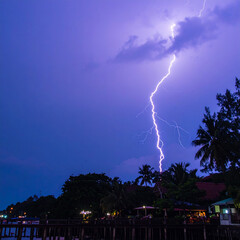 A dramatic lightning strike illuminates the dark stormy sky with electric blue brilliance
