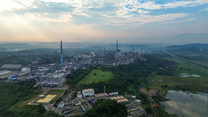 Aerial drone view of a large industrial factory complex with warehouses, chimneys, and storage tanks in Asia